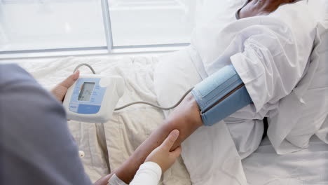 diversa doctora midiendo la presión arterial de una paciente de edad avanzada en una habitación de hospital, en cámara lenta