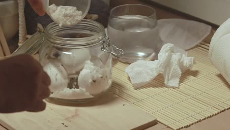adding sea salt to raw eggs in a mason jar to make preserved salted eggs showing slow living and sustainable lifestyle