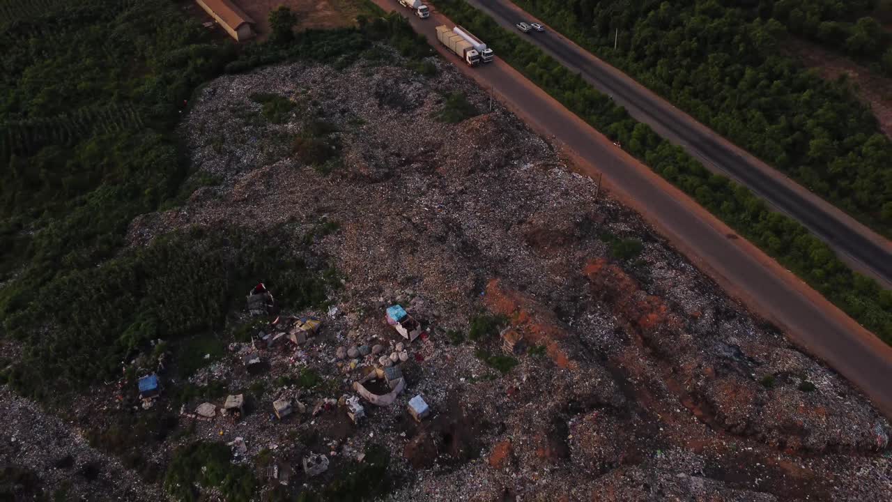 Stunning aerial of a large open landfill surrounded by green nature and a busy road in Nigeria, Africa