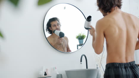 hombre secándose el cabello en el baño