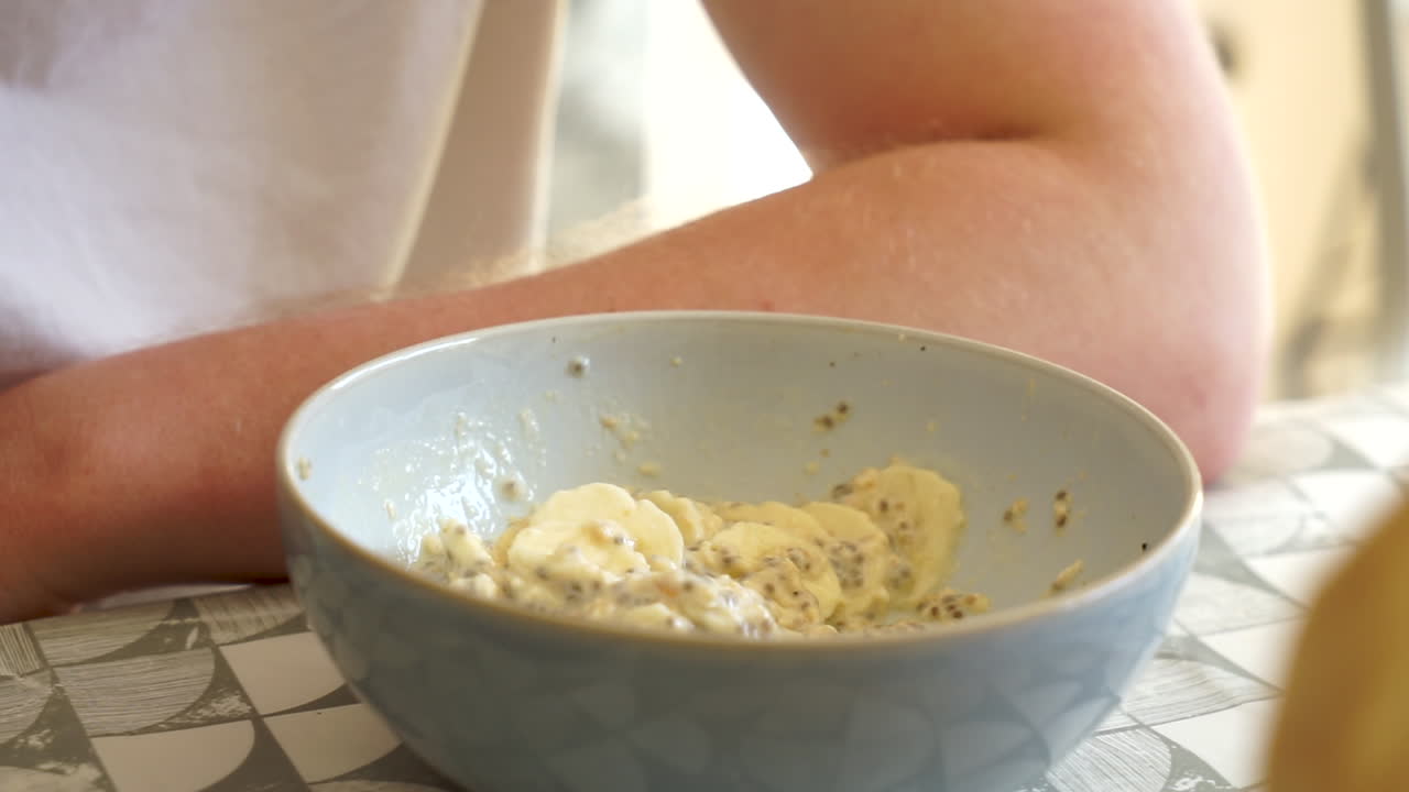 joven comiendo un desayuno saludable, vegetariano y vegano plátanos picados, yogur y semillas de chía