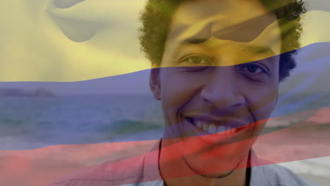 animation of flag of colombia waving over smiling african american man standing against sea