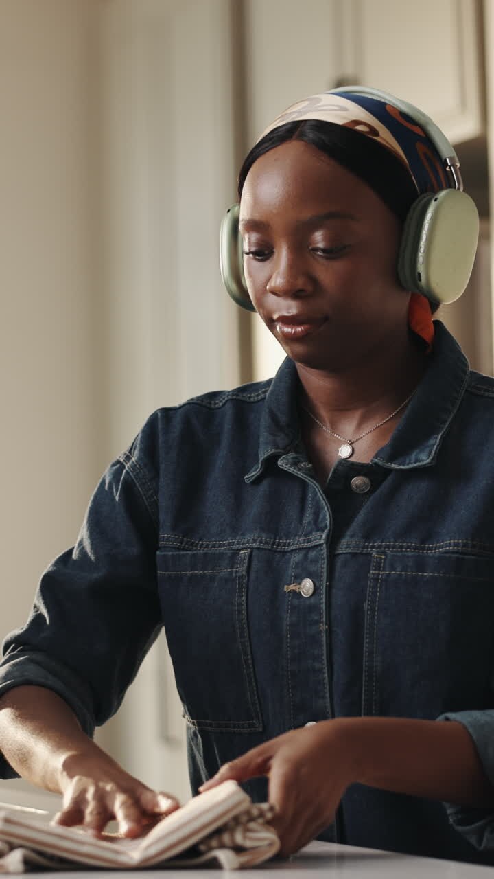 Happy Young Woman Listening to Music While Folding Laundry at Home
