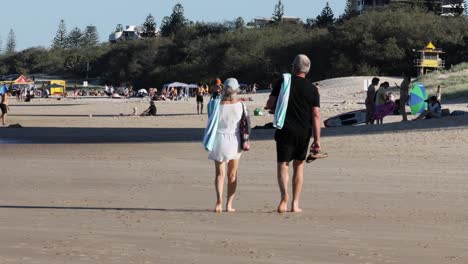 two people walking on a beach with others