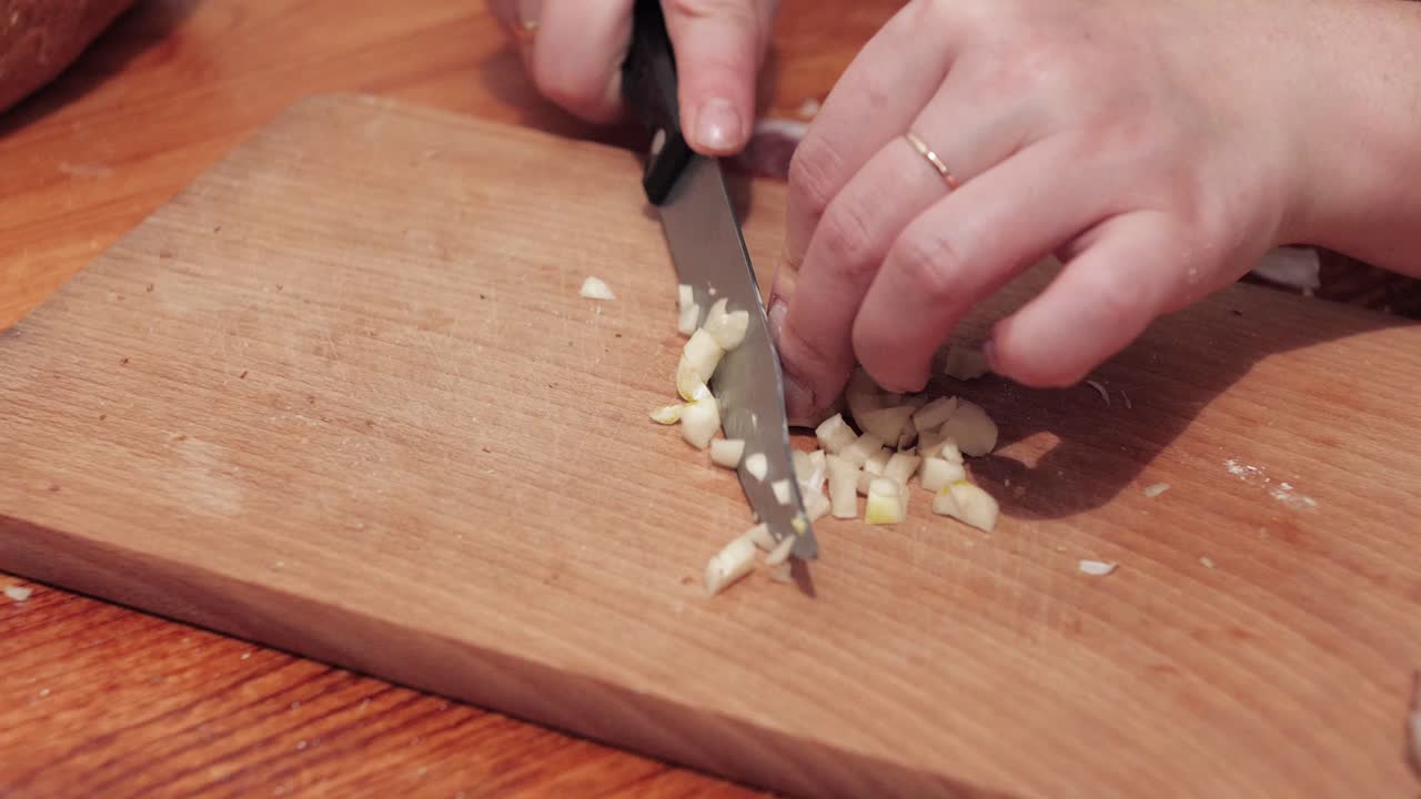 Woman's hands chop the last clove of garlic