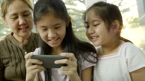 4k asian daughters playing games on smart phone with mother, happy time together