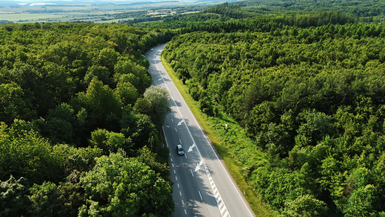 Footage over the highway with few cars riding by. Green countryside in summer. Top view.