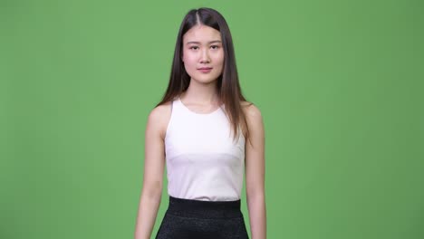 젊은 아름다운 아시아 사업가 여성이 위를 가리키고 있습니다.