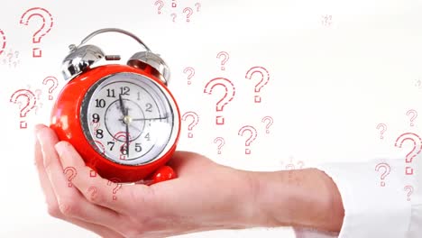 Animation-of-multiple-question-symbols,-cropped-hand-holding-alarm-clock-against-white-background