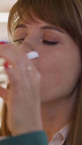 woman drinks water from glass to swallow pill feeling unwell on blurred background. lady stands in shop of dietary supplements closeup slow motion