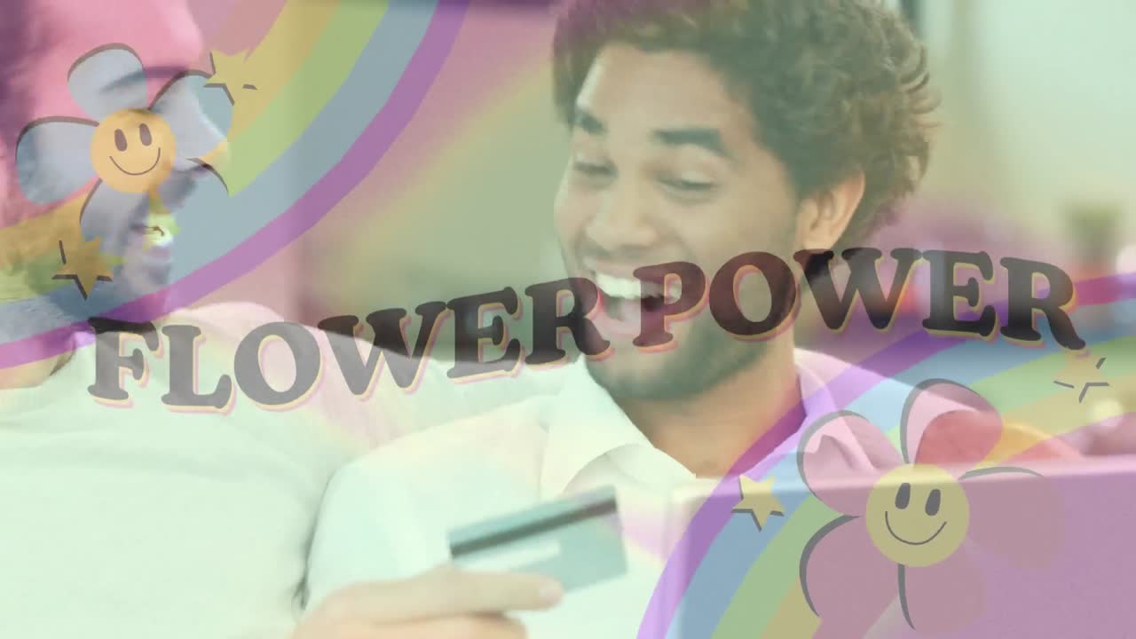 Animation of flower power text with rainbow and flowers over happy gay man couple paying online