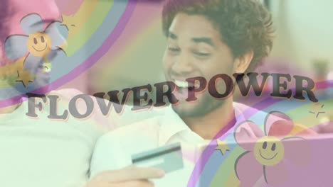 Animation-of-flower-power-text-with-rainbow-and-flowers-over-happy-gay-man-couple-paying-online