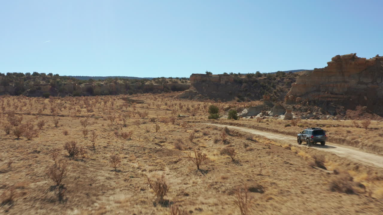 원격 비포장 도로의 사막 풍경을 통해 차를 따라가는 공중, 4k