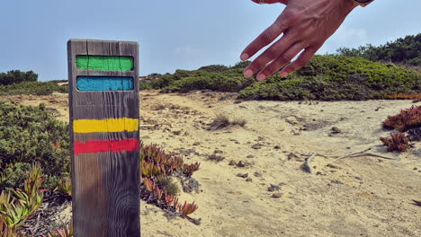 female backpacker touches trail marker on fisherman's trail in portugal