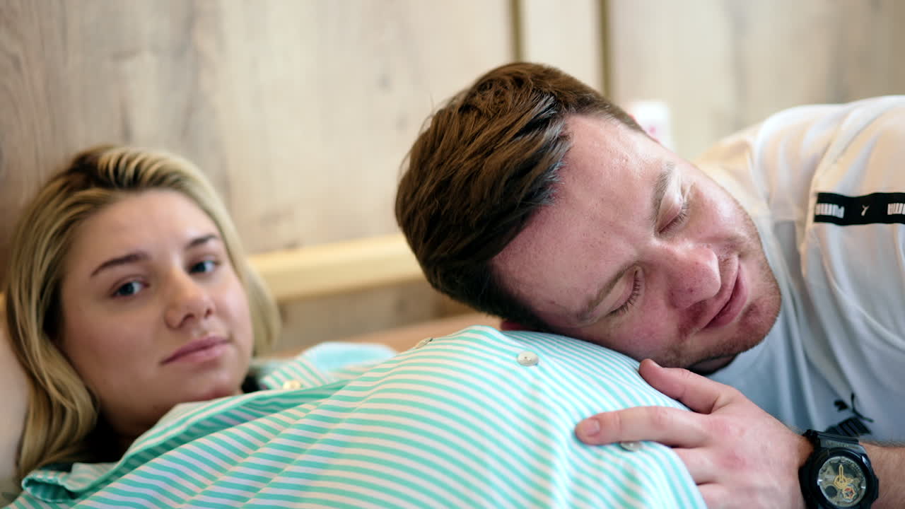 Expecting parents in the maternity hospital. Happy father put his ear to the wife's belly listening to baby kicks.