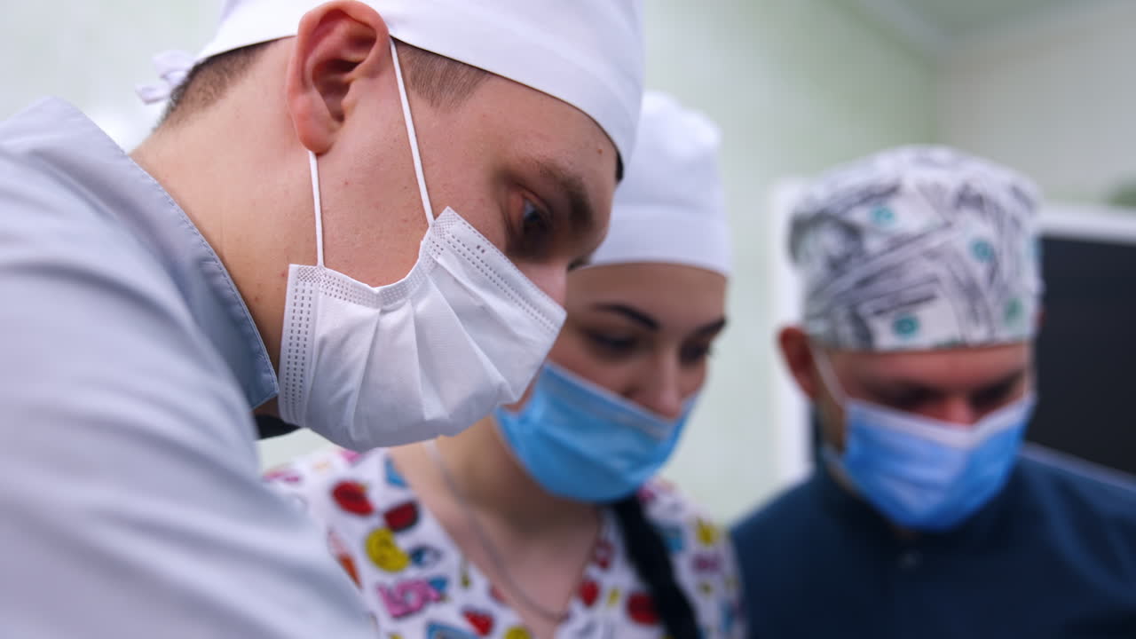 Focused faces of students in masks and caps listening to their teacher. Future dentists are taught through practice. Close up.