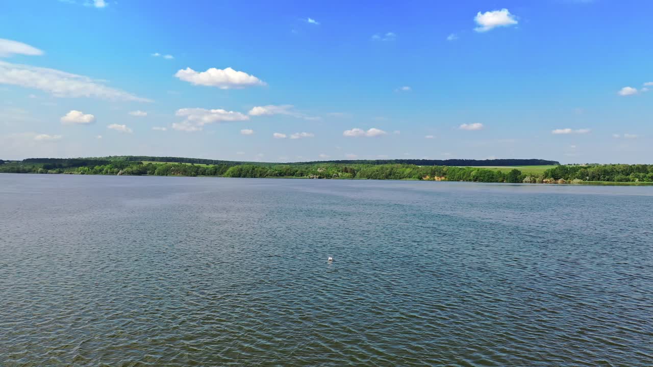 Panoramic view of beautiful river. Blue water on green nature background in bright daytime. Flight over the river. Aerial view.
