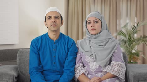 muslim couple watching tv at home