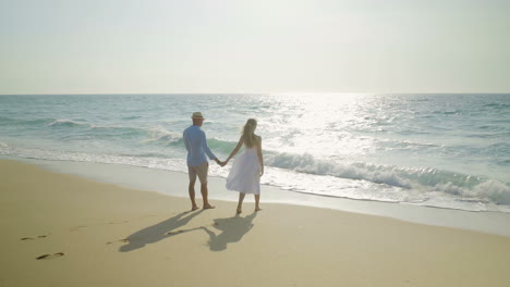 couple holding hands and walking at seaside