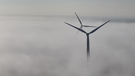 misty ground fog surround windmills during the early morning day break