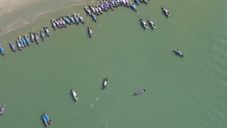 top down drone shot of longtail boats floating in the water next to the beach in ao nang thailand