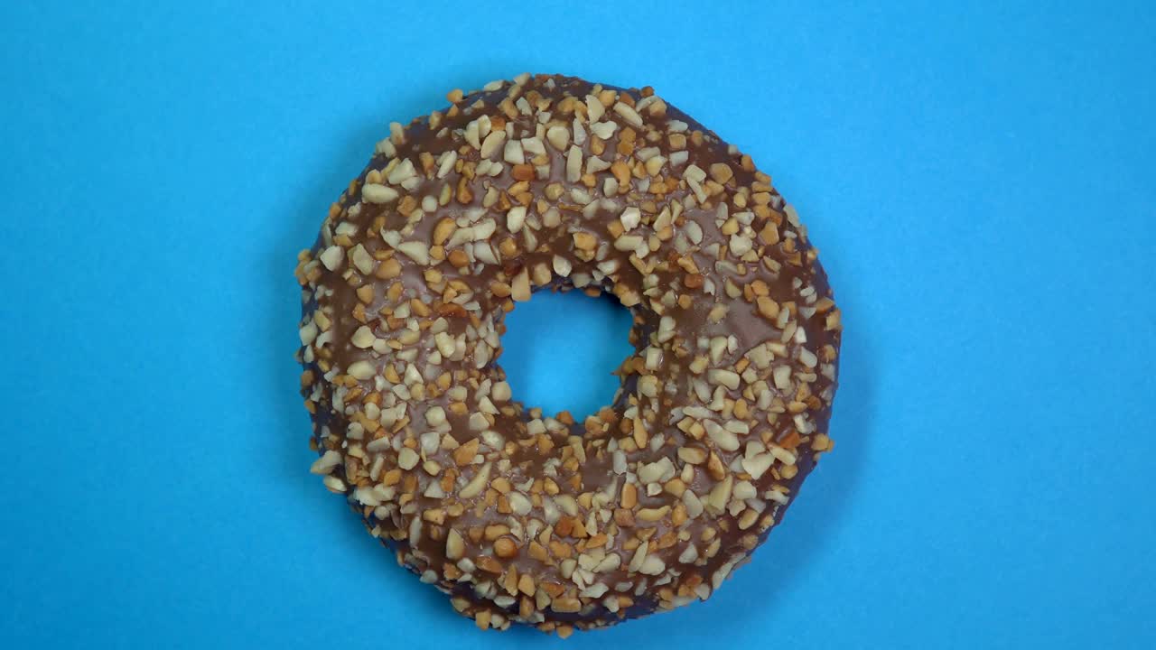 вкусный и свежий посыпанный пончиком крупный кадр макро, вращающийся на синем фоне.