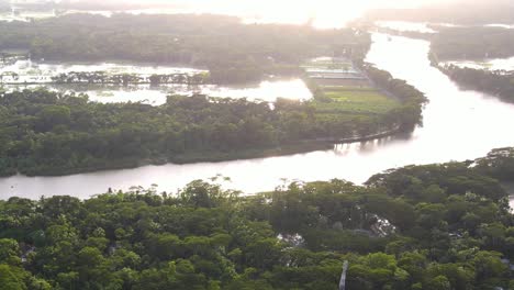 空中景象: 洪水泛濫的河流,農田和熱帶森林被洪水淹沒, 嚴重的光線反射, 災難