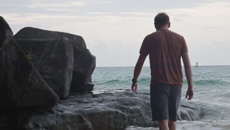 rough waves on the rocks with a man approaching the beach of dam trau, con dao island, vietnam