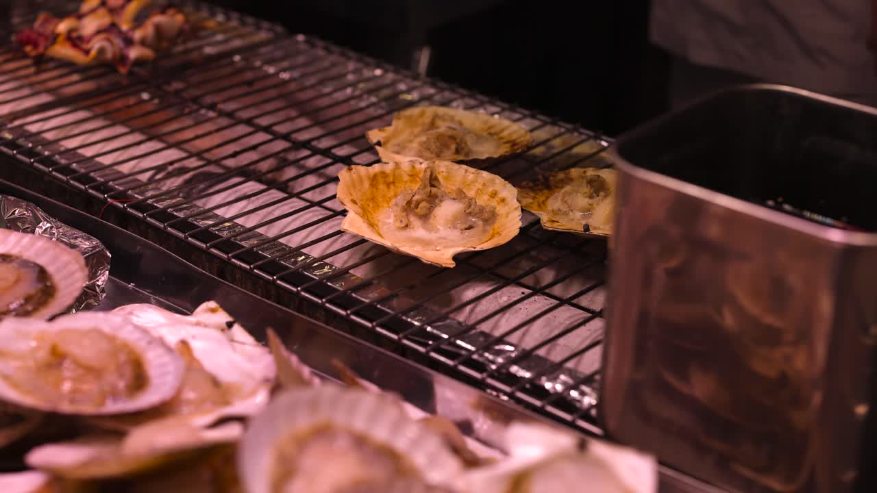 Hotate scallops cooking on a smoky grill