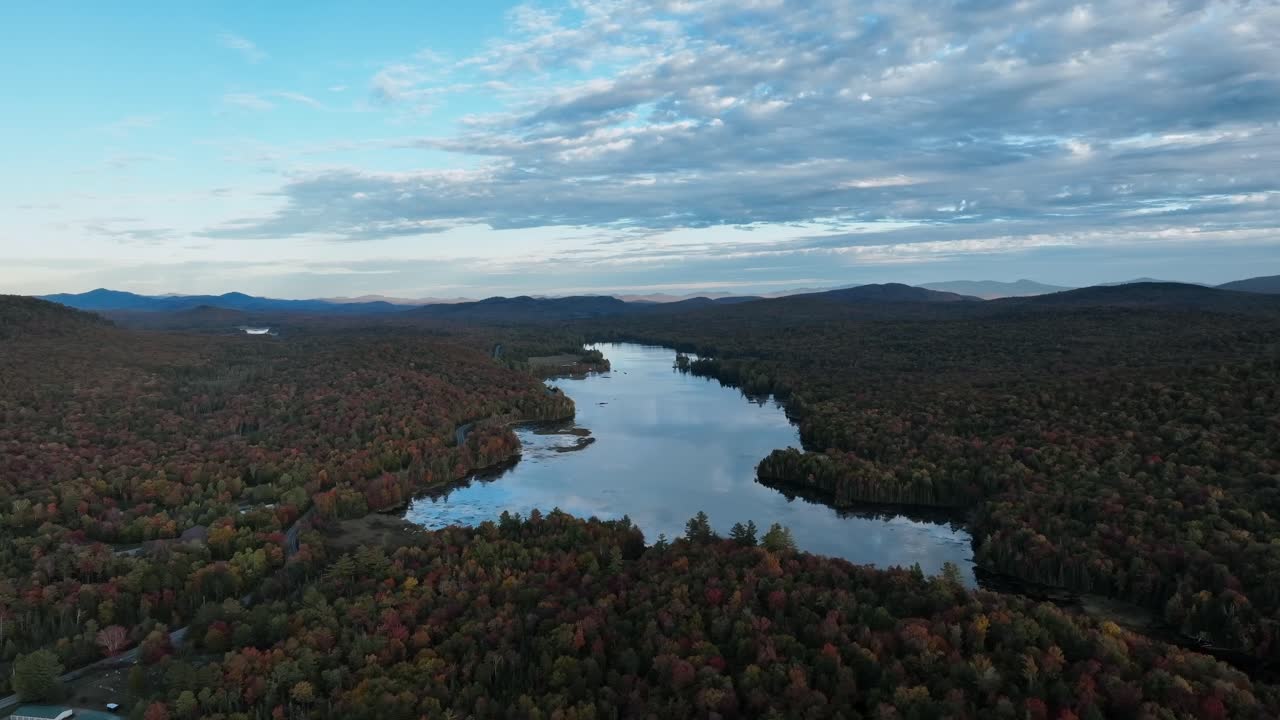 río rodeado de denso matorral con follaje de árboles de otoño durante la puesta del sol
