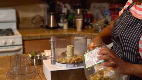 Primer-Plano,-Mujer-Negra-Sacando-Anacardos-En-El-Procesador-De-Alimentos