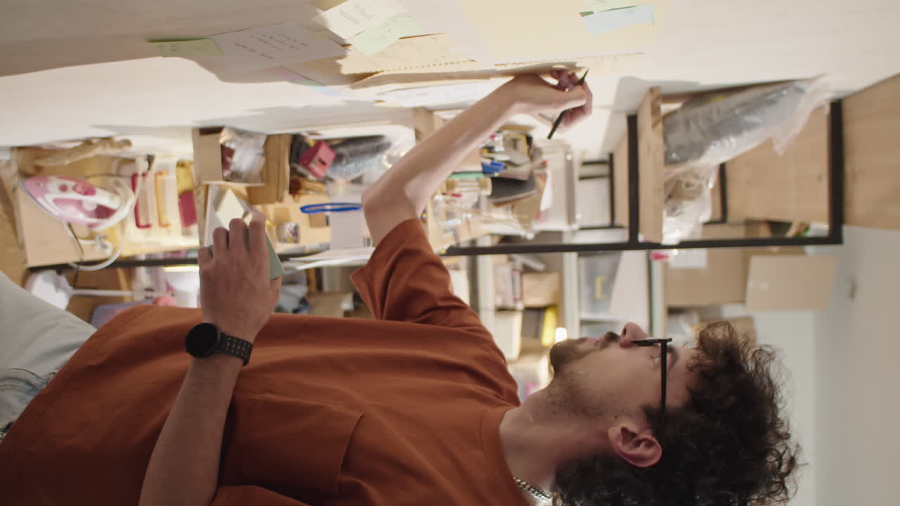 Man Writing on Stickers on Wall in Warehouse