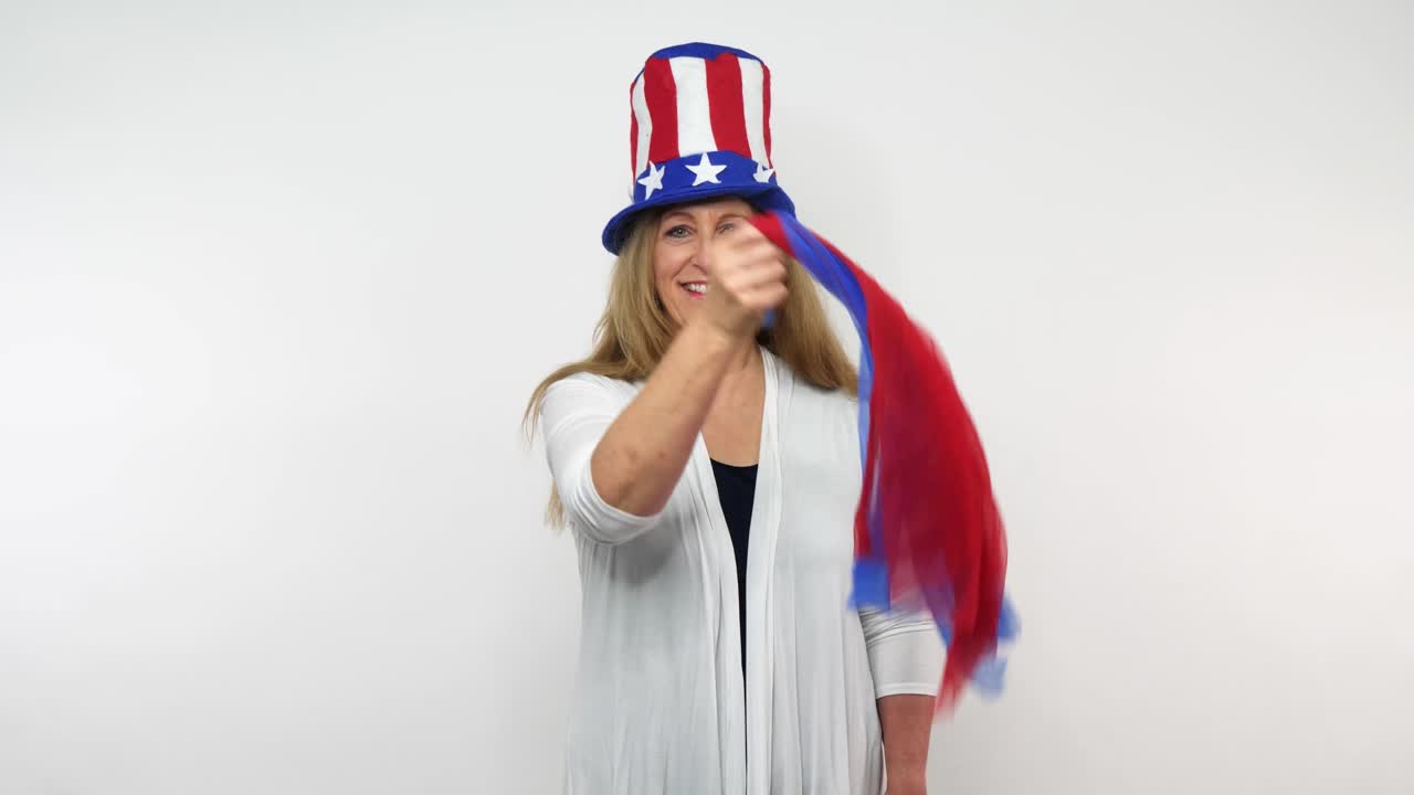 una anciana balancea un par de bufandas rojas y azules mientras usa ropa patriótica