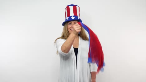 a senior woman sways a pair of red and blue scarves while wearing patriotic clothing