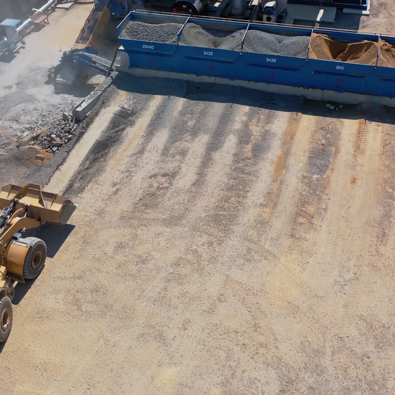 Bulldozer working with gravel outdoors. Industrial machine carrying rubble into into special containers. Asphalt factory. Aerial view.