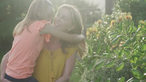 senior caucasian woman carrying her granddaughter spending time in garden