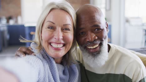 happy senior diverse couple in living room sitting on sofa, making video call