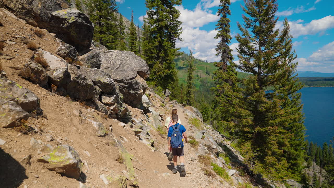 Two Hikers on a Scenic Mountain Trail Overlooking a Lake