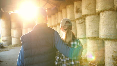 rear view of caucasian young couple walking in a stable with hay stocks