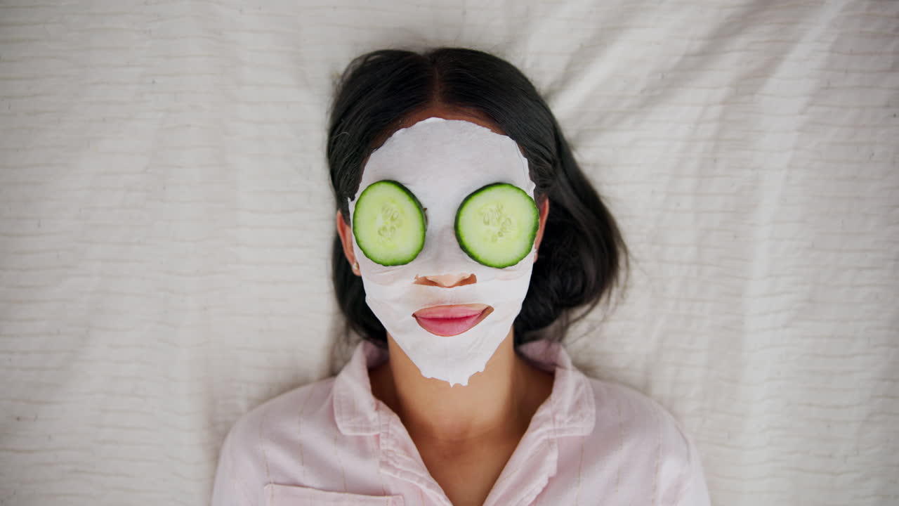 Woman with face mask and cucumber slices on eyes
