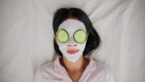 woman with face mask and cucumber slices on eyes