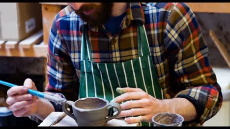 male artist painting on earthenware bowl