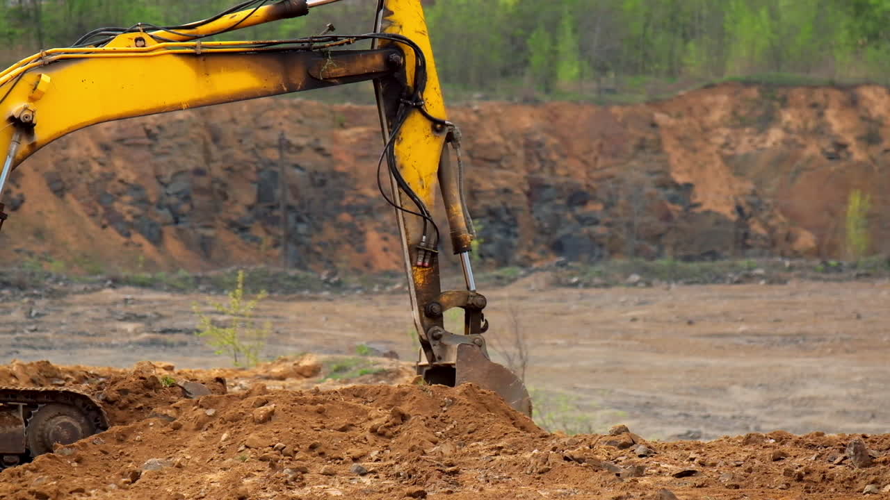Excavator bucket digs up soil. Excavator iron bucket scoops up the ground. Excavator shovel digging on nature background. Slow motion.