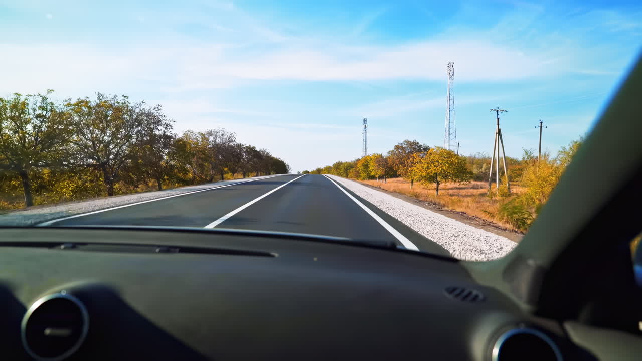Lonely road in Moldova with autumn trees by the side. View from the car. Travel and journey ideas