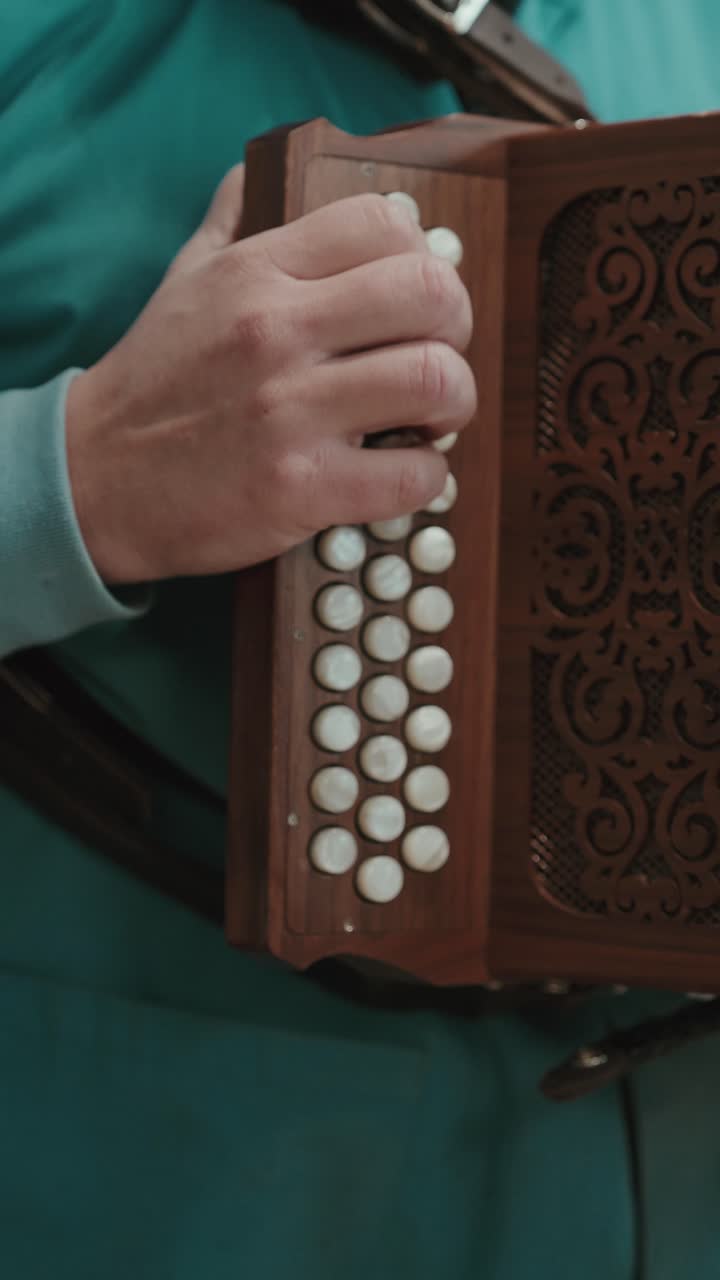 Primo piano di una mano che preme i tasti di una concertina su uno strumento in legno durante un'esibizione o una prova in Portogallo, con inquadratura verticale.