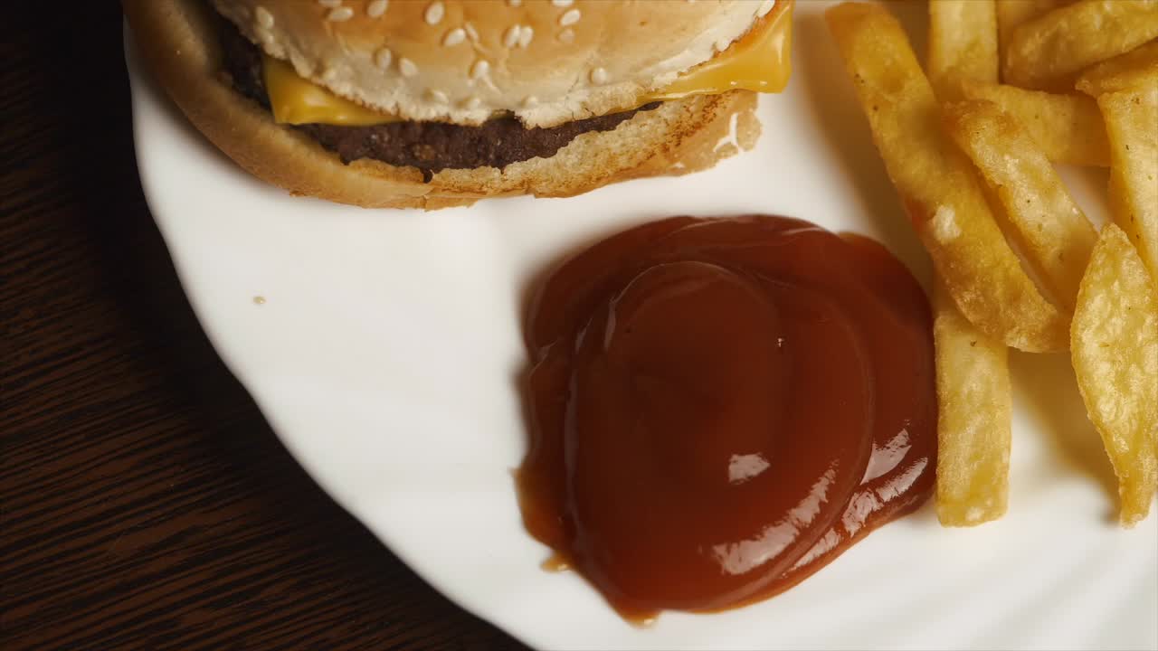 Mano che intinge patatine fritte nel ketchup con un hamburger e patatine