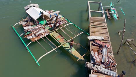 a filipino man unloading scrap metal from a small boat and placing it on a wooden pier