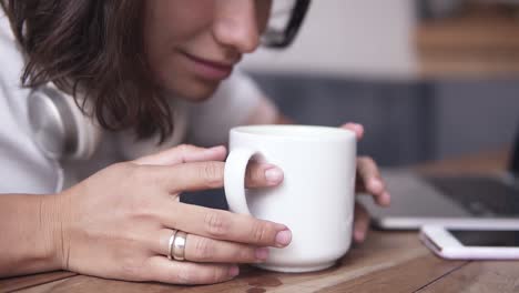 close up footage of a gorgeous brunette girl sitting by the table. the girl leans over the cup and inhales the fragrance. slow motion