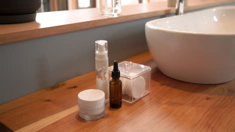 skincare products neatly arranged on wooden bathroom counter near sink, copy space