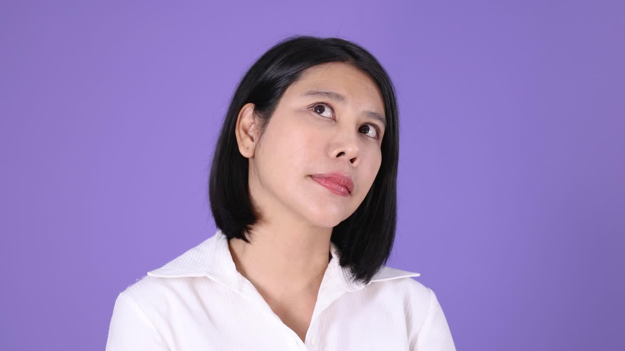 Asian woman rolls eyes and tilts head, expressing annoyance, under even lighting, static camera